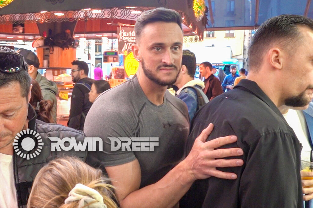 Bodybuilder in public video wearing compression shirt. Bodybuilder squeezing himself through the crowds.